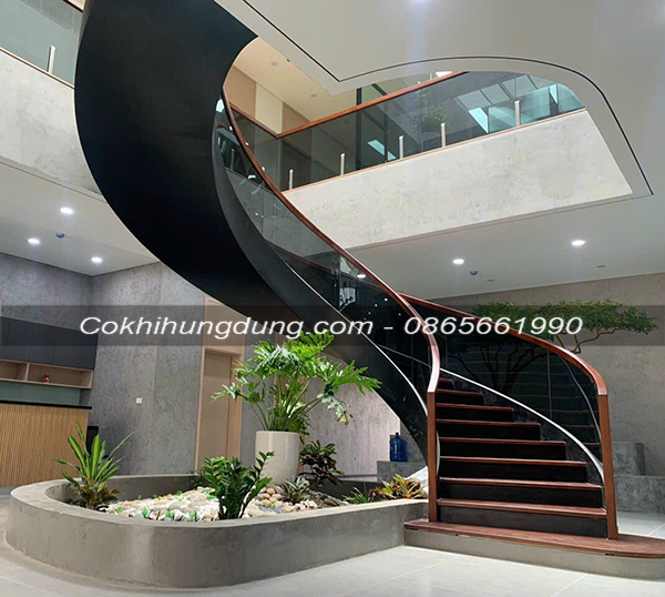 Mẫu thiết kế cầu thang xương xoáy lan can kính xanh đen cho không gian biệt thự